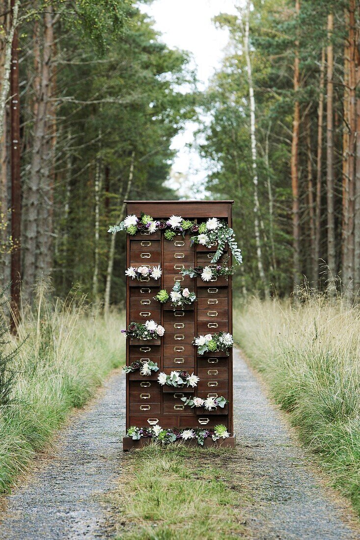 Antique chest of drawers with flowers hanging out of the drawers