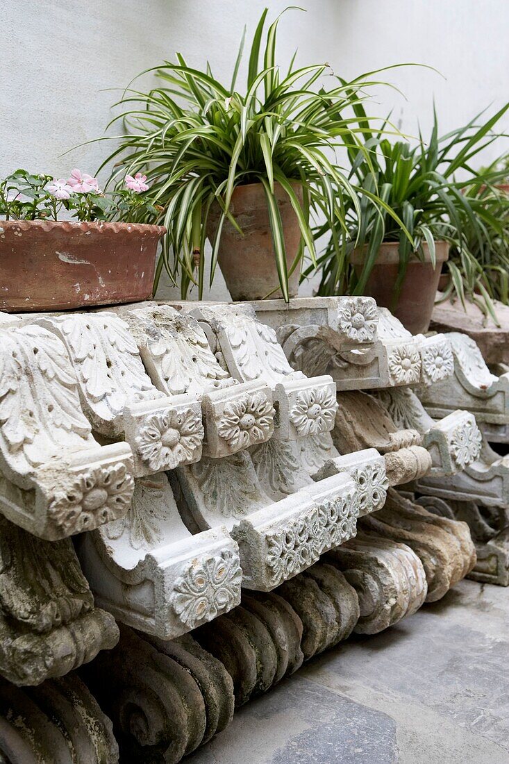 Architectural salvage in a courtyard with pot plants