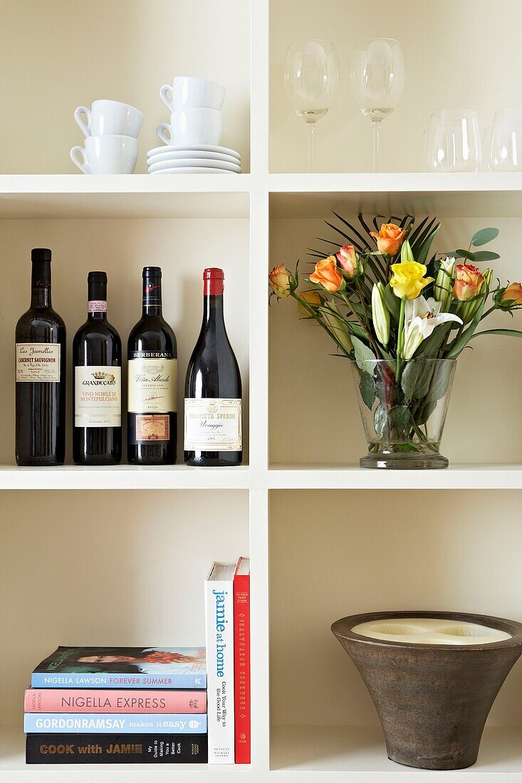 Wine bottles and cut flowers on shelving unit