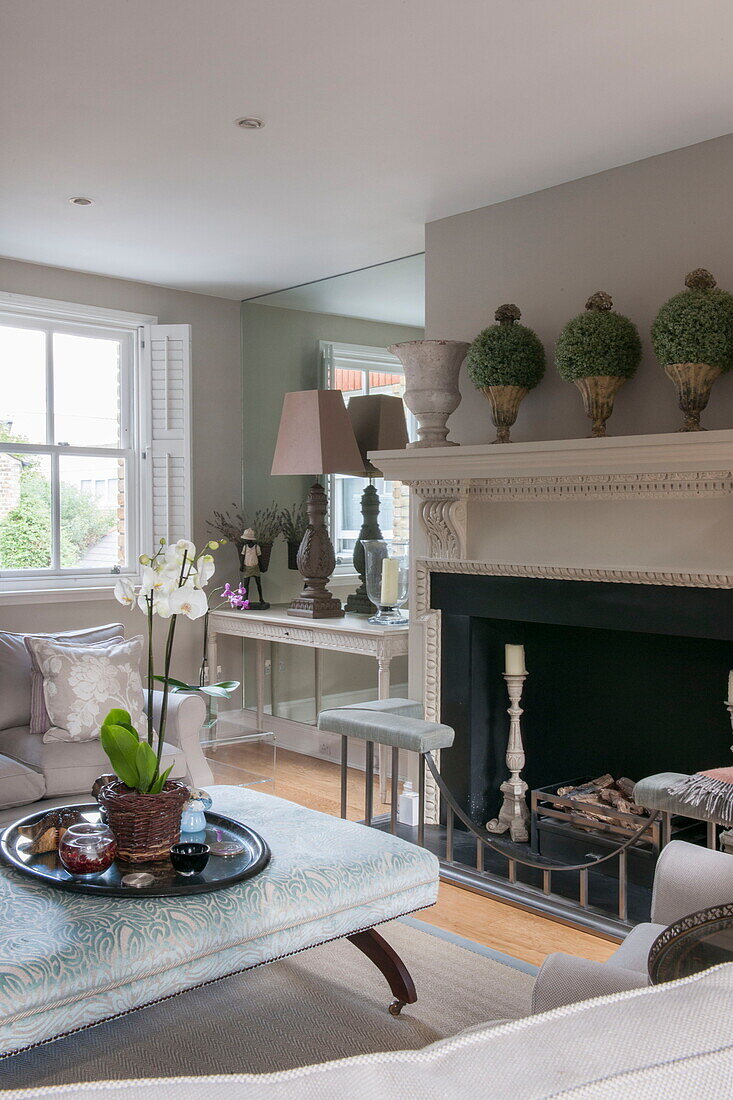 Orchid on ottoman footstool in front of fireplace in Battersea home,  London,  England,  UK