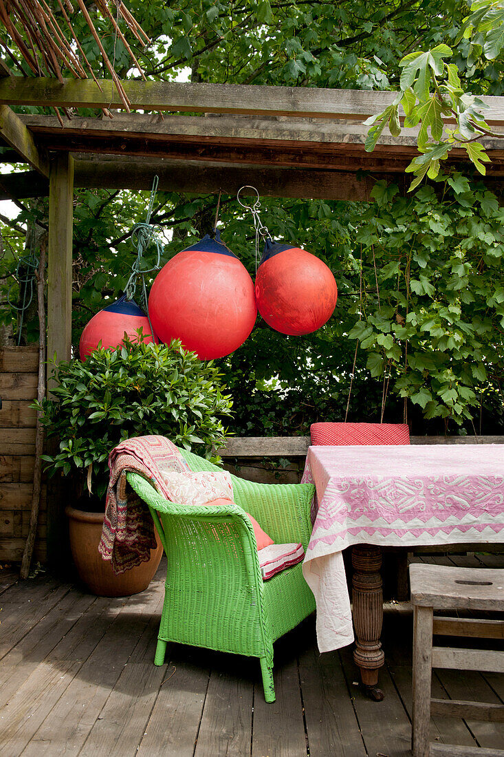 Green wicker chair at table on decked terrace of contemporary Lewes home,  East Sussex,  England,  UK