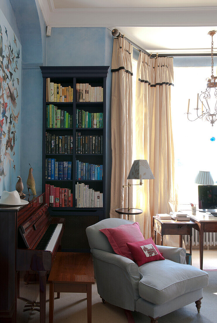 Armchair and bookcase with piano in Tiverton country home,  Devon,  England,  UK