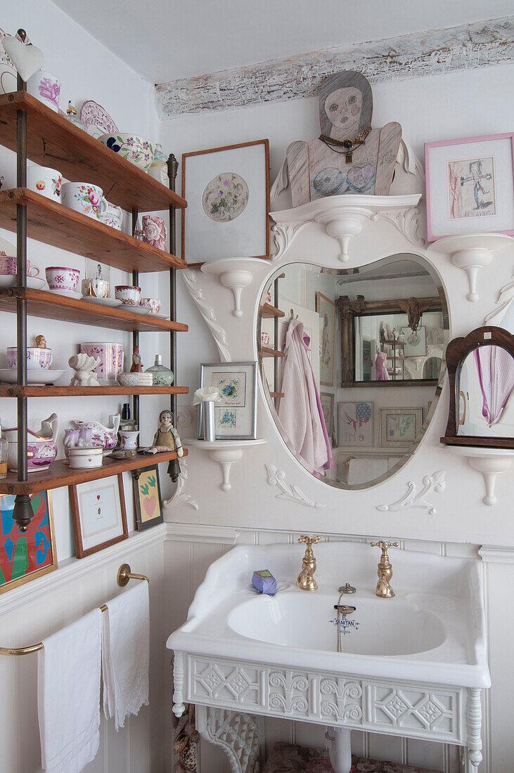 Porzellansammlung auf hölzernen Badezimmerregalen mit Spiegel über dem Waschbecken in einem Haus in Dorset, Kent, Großbritannien