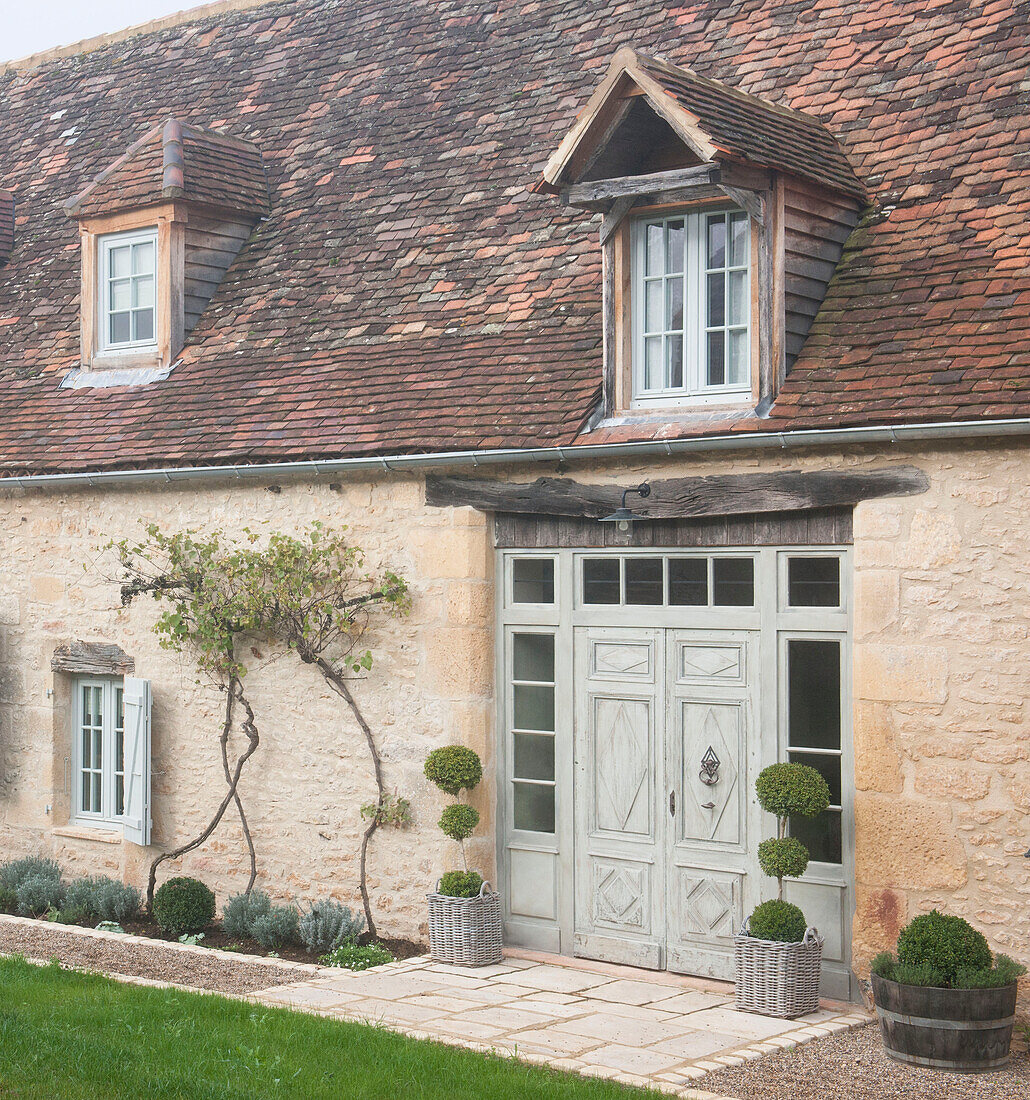 Dormer windows in tiled roof above double doors of Dordogne cottage  Perigueux  France