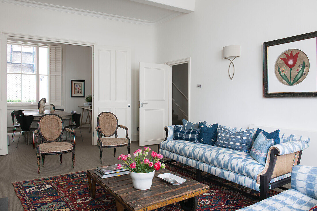 Blue and white sofa with cut flowers on low wooden coffee table in South Kensington townhouse  London  UK