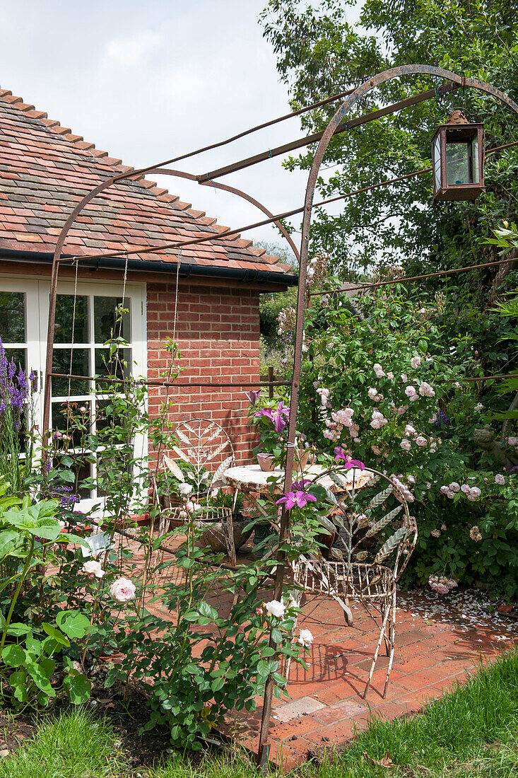 Metal pergola on brick patio with metal furniture outside Ashford cottage  Kent  UK