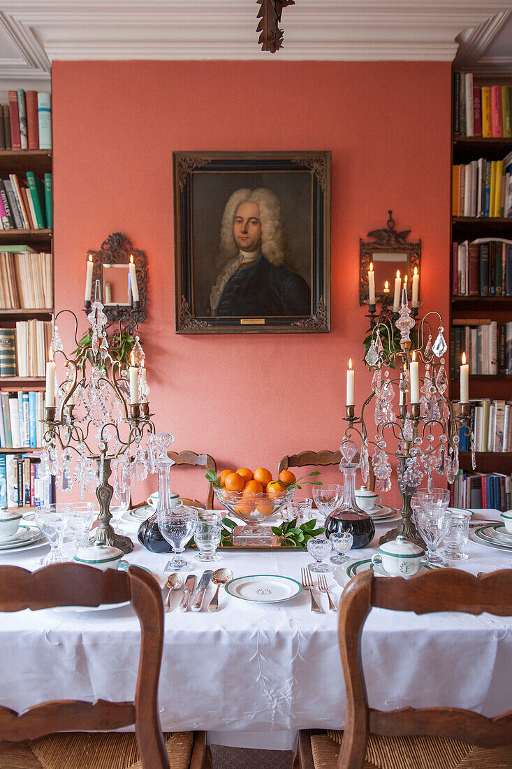 Dining table with bookshelf and glass candelabras in London home  England  UK