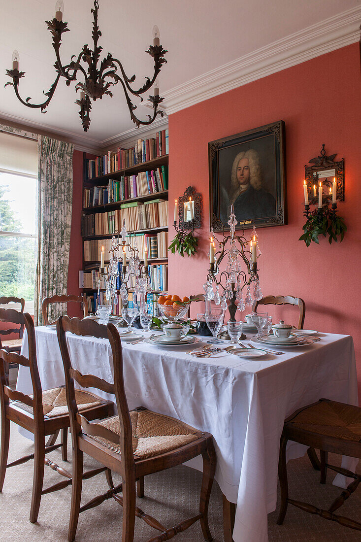 Dining table with bookshelf and glass candelabras in London home  England  UK