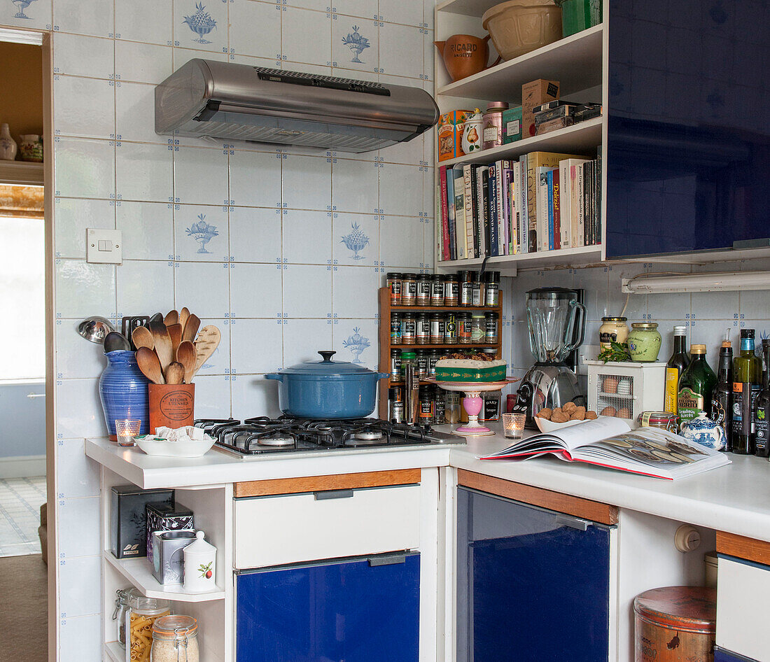 Wooden spoons and spice rack with casserole on hob in blue fitted London kitchen  England  UK