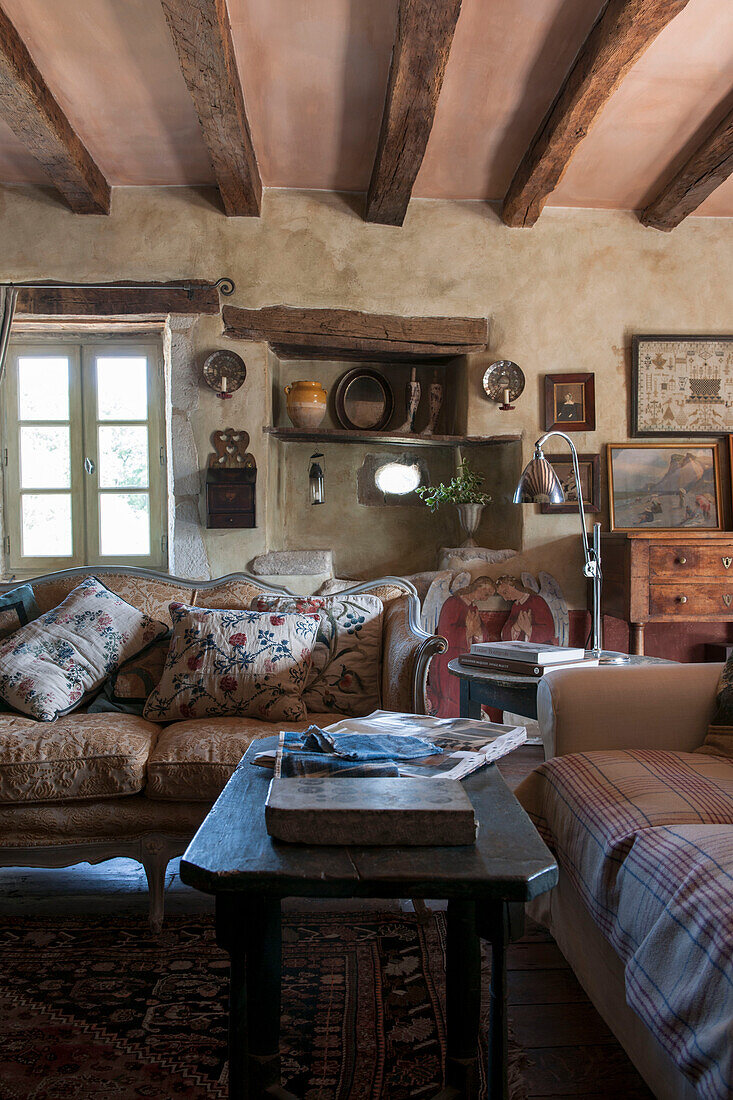 Bestickte Kissen auf einem Sofa mit Nischenregal in einer umgebauten Scheune in Lotte et Garonne, Frankreich