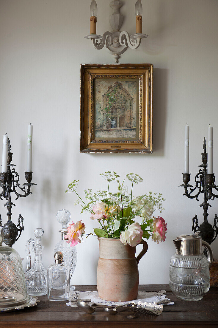 Terracotta hug and candlesticks with cut roses on wooden sideboard in Dordogne farmhouse  Perigueux  France