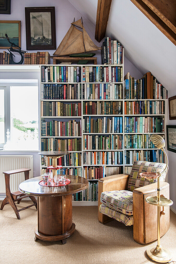 Vintage Stuhl und Tisch mit Bücherregal am Fenster in Norfolk coastguards cottage England UK