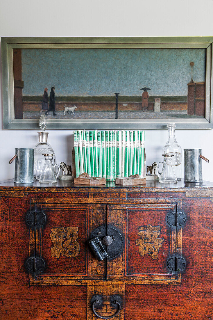 Framed artwork above Chinese cabinet with ornaments in Norfolk coastguards cottage  England  UK