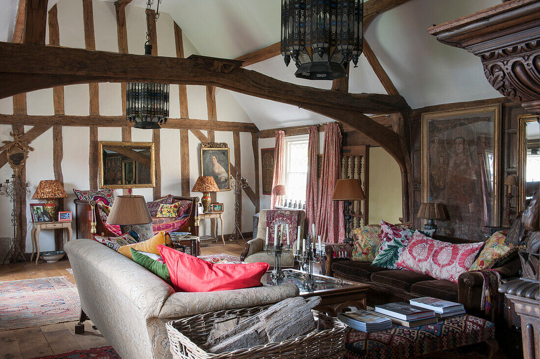 Log basket and sofas in timber farmed living room of Suffolk home  England  UK