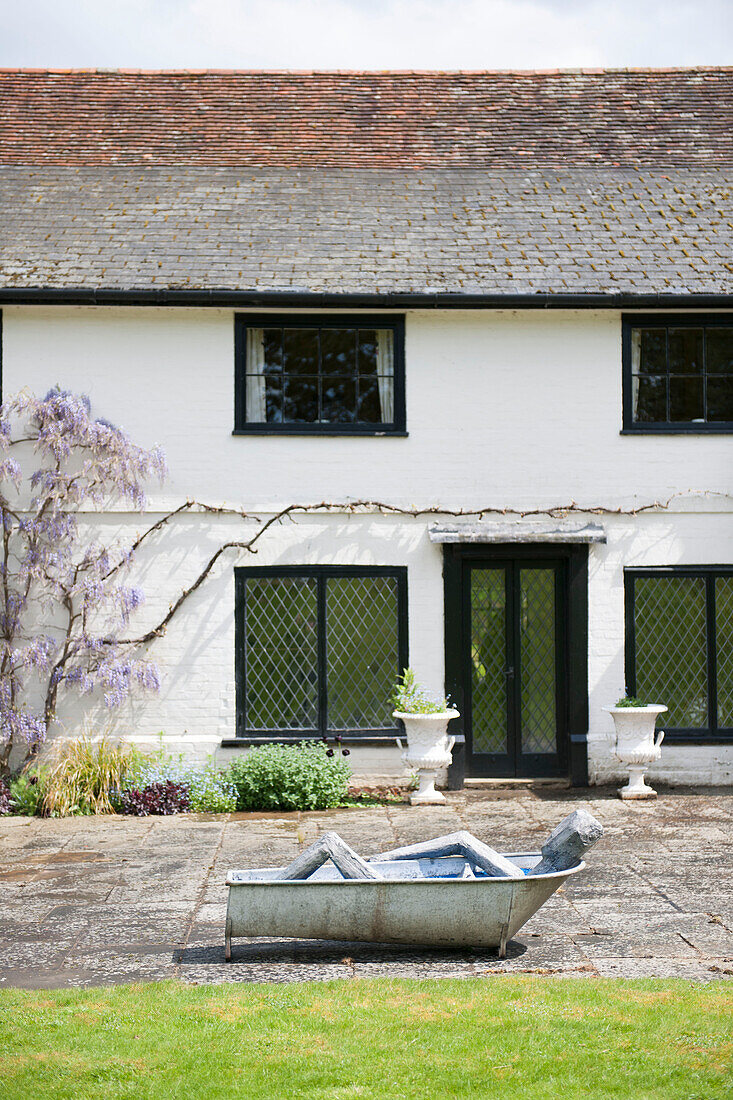 Sculpture of a man in a bath on terrace of Suffolk farmhouse  England  UK