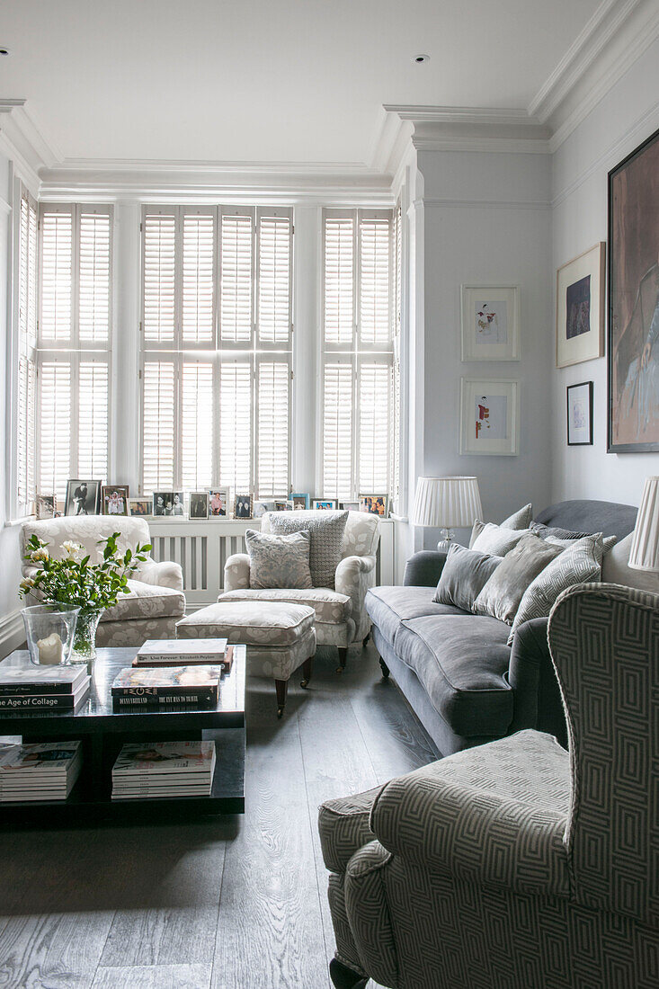 Geschlossene Fensterläden mit Sesseln und Couchtisch im Wohnzimmer eines viktorianischen Reihenhauses im Süden Londons