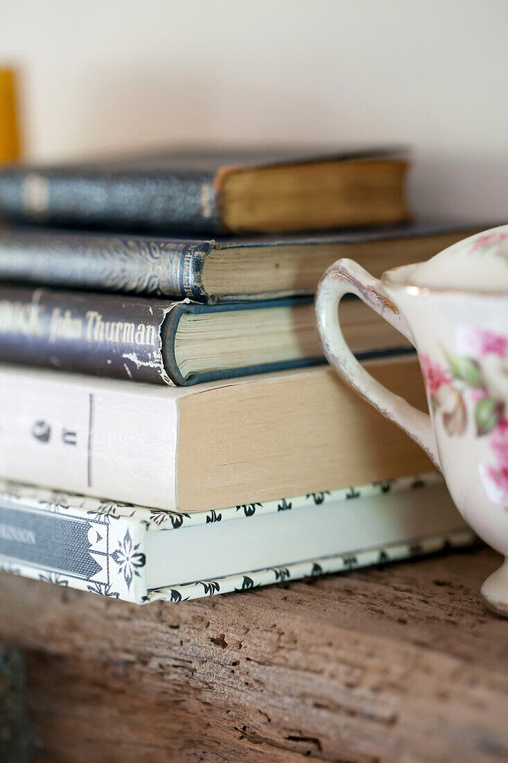 Hardbacked books and china on wooden shelf in Amberley cottage West Sussex UK