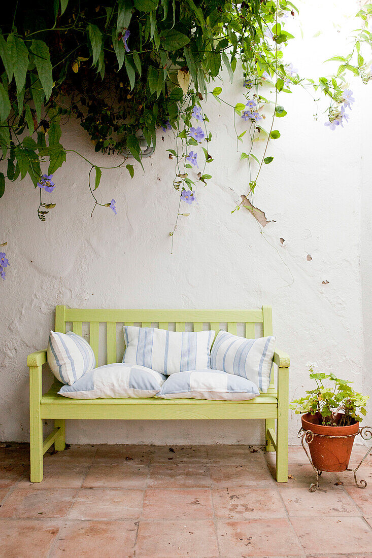 Sitzbank mit Kissen und blühenden Pflanzen in einem ummauerten Innenhof in Castro Marim Portugal
