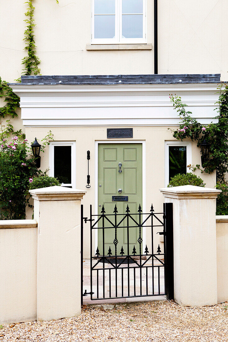 Cream facade of Amberley home with wrought iron gate and gateposts West Sussex England UK