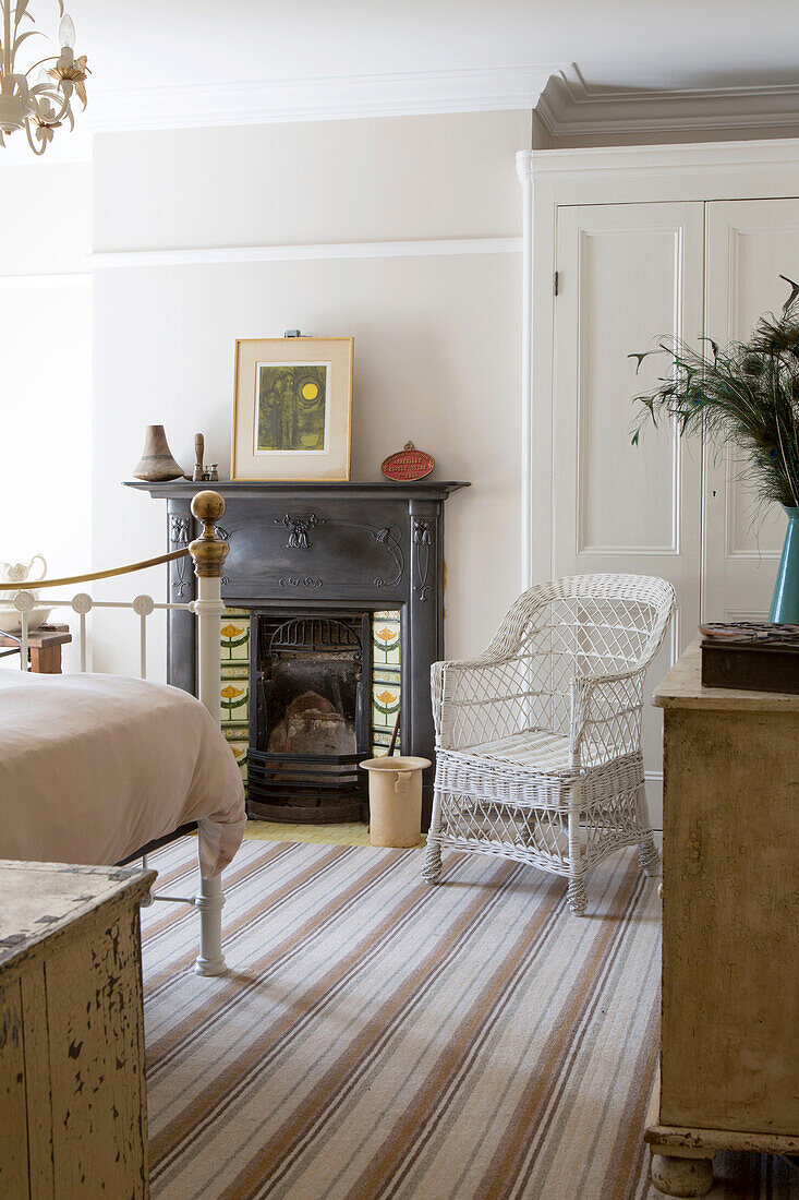 Wicker chair at fireside with striped rug in Edwardian West Sussex townhouse England UK