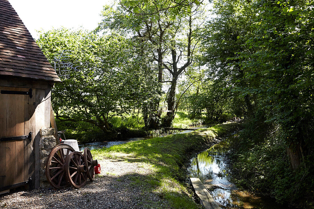 Old iron cartwheels in sunlit exterior with stream,  United Kingdom