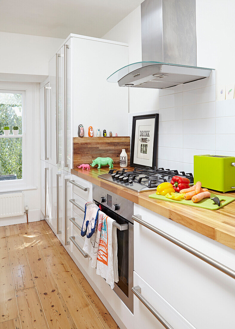 Teeservice und Croissants mit lindgrünem Wasserkocher in einer weißen Einbauküche in einem Londoner Haus, England, UK