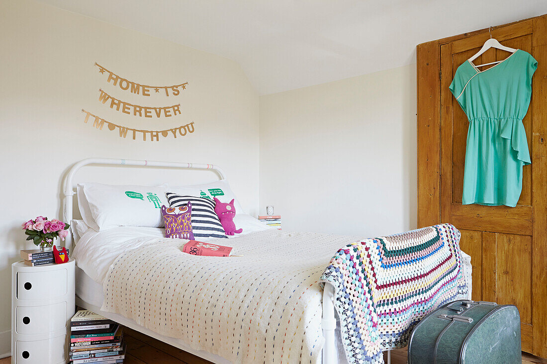 Single bed with crochet blanket and blouse hanging on back of door in London bedroom,  England,  UK