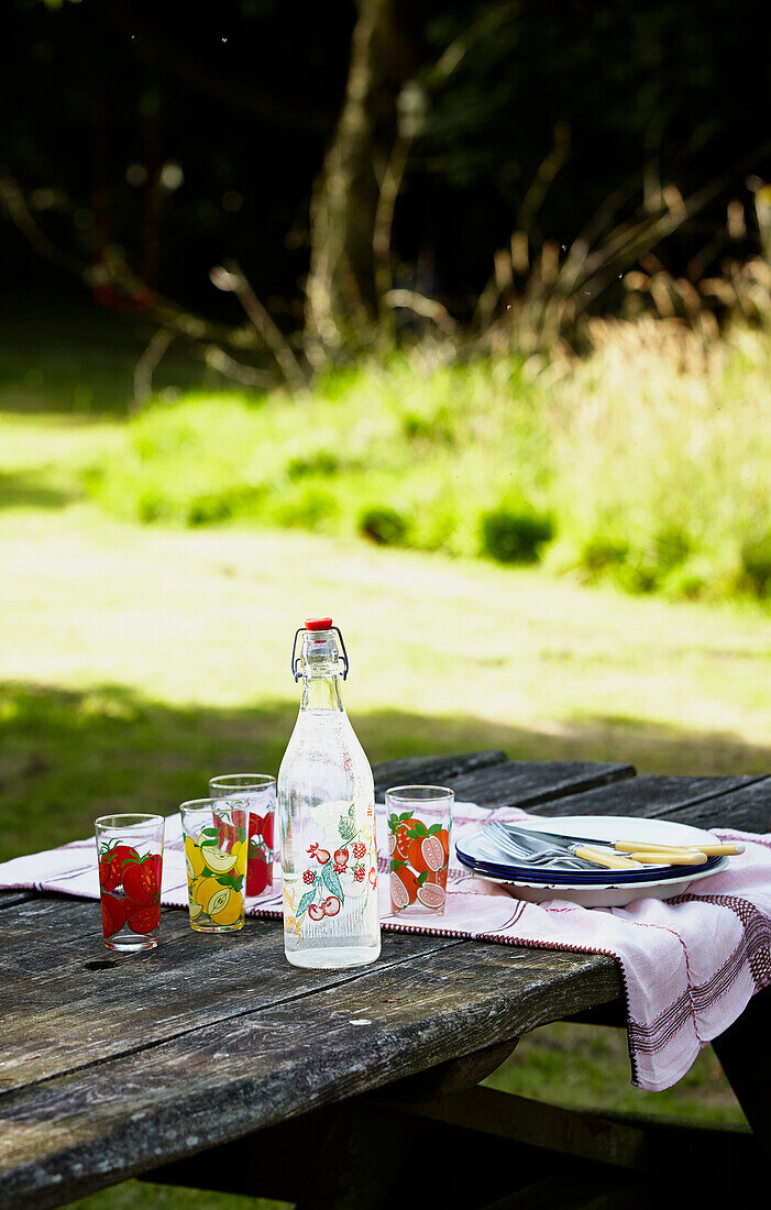 Vintage bottle and plates on picnic table in Brabourne garden,  Kent,  UK