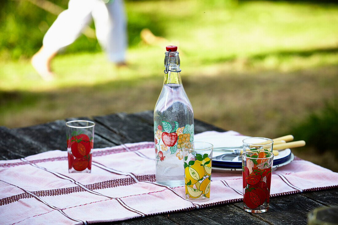 Flasche und Teller auf Picknicktisch im Garten von Brabourne, Kent, Großbritannien