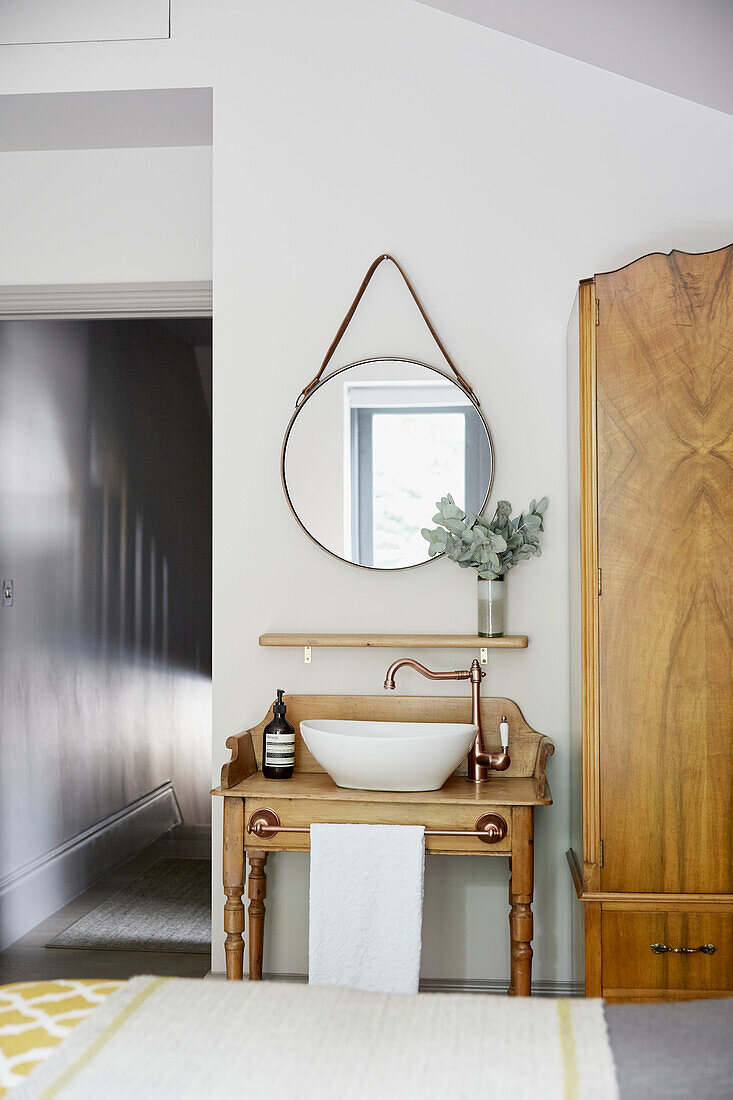 Vintage mirror above wash stand with wardrobe in East London townhouse  England  UK