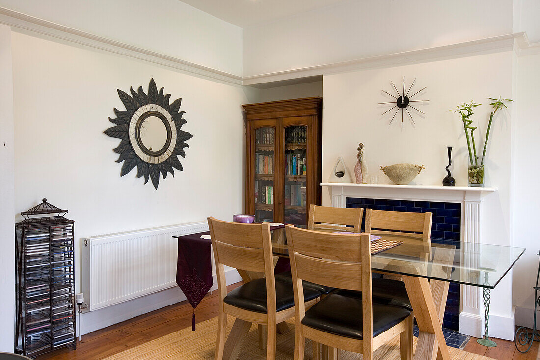 Glass topped dining table and mirror with leaf surround in New Malden home, Surrey, England, UK