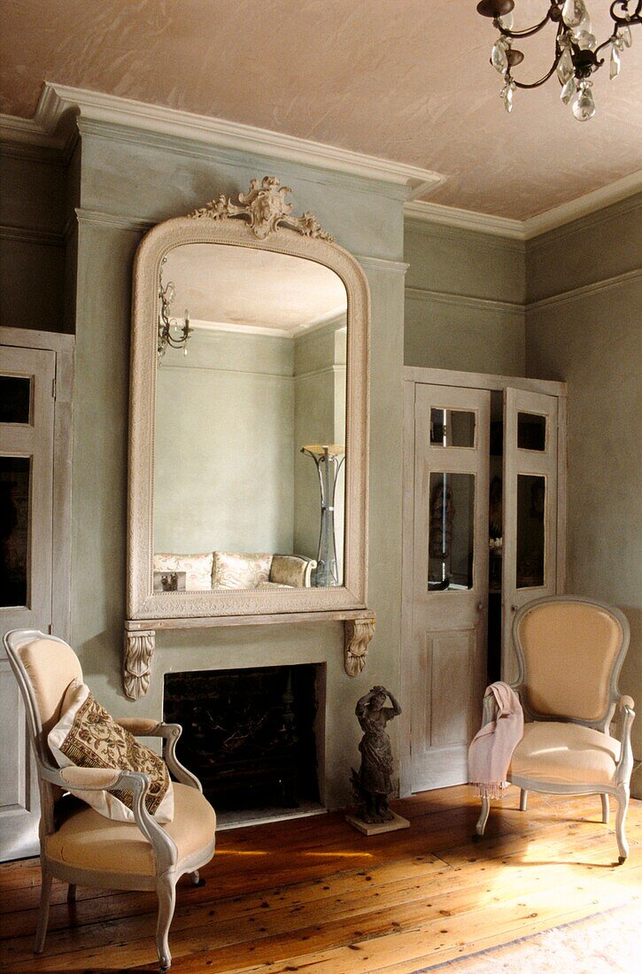 Fireplace setting in soft grey living room with two French fauteuils 