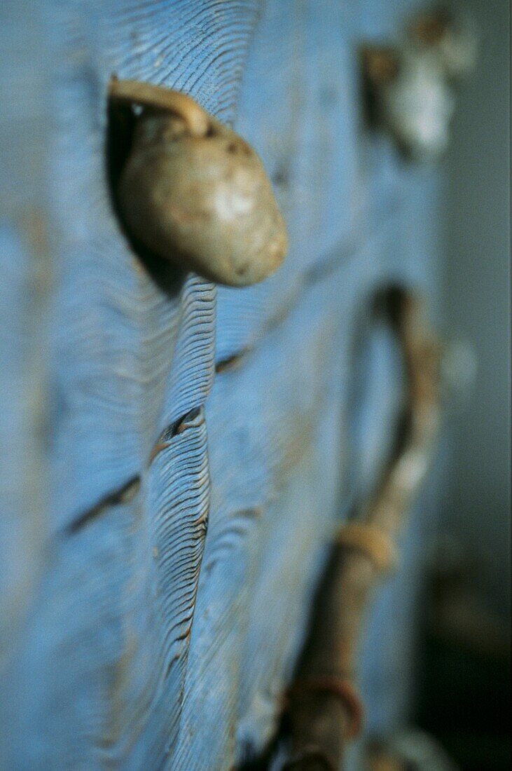 Close up of pebble drawer handle on stained blue chest of drawers