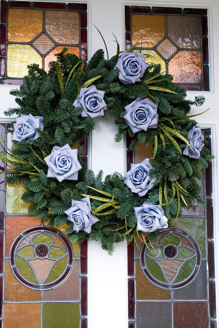 Weihnachtsblumen auf Kranz in Buntglasfronttür