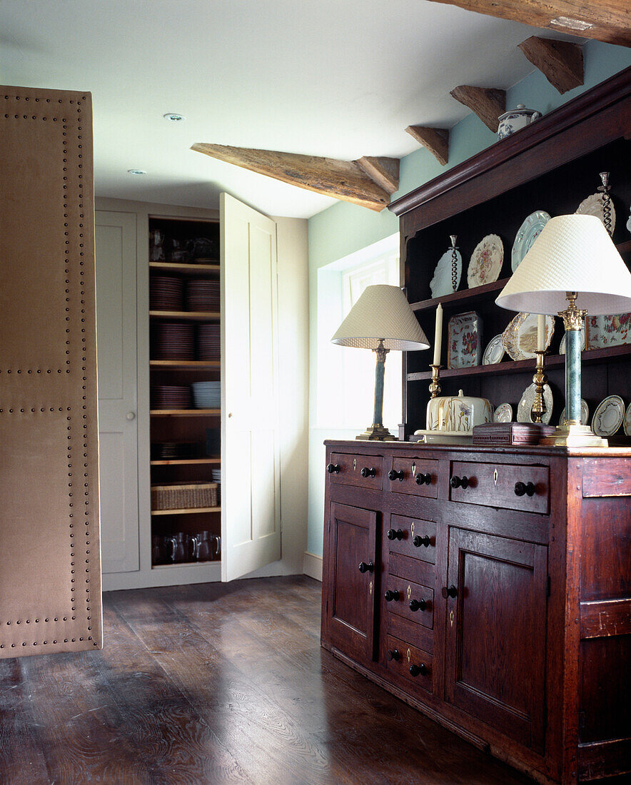 Floor to ceiling cupboards and an old oak dresser with a china collection of Victorian scallop edged plates and silver topped perfume jars 