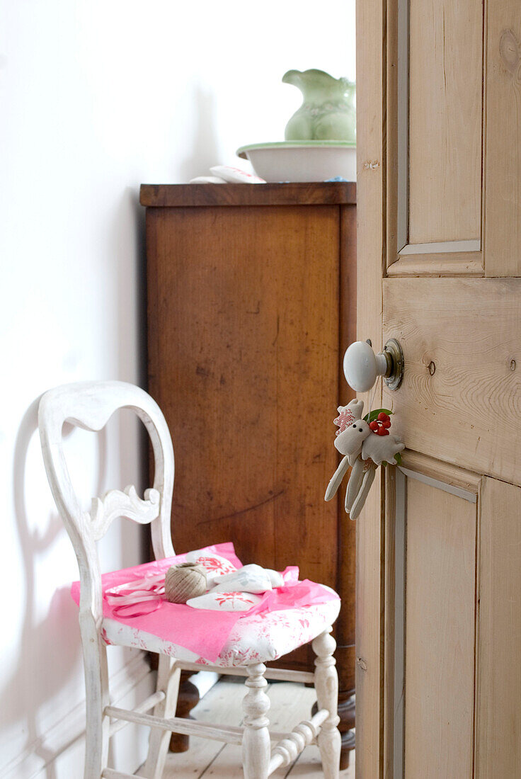 View through stripped pine bedroom door with soft toy christmas reindeer decoration hanging from a porcelain door knob