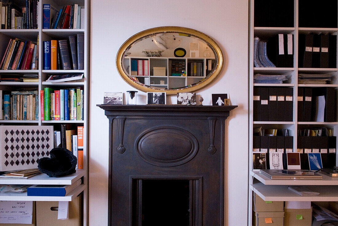 Ovaler Spiegel über Kamin mit Bücherregalen und Ablage