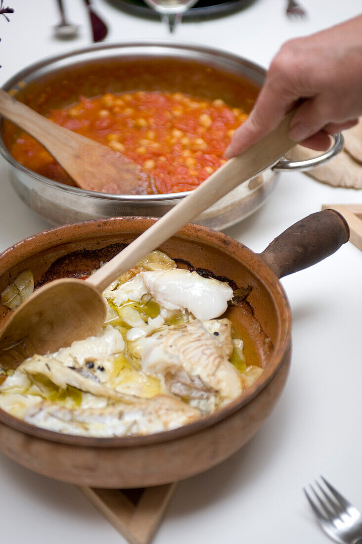 Kochtöpfe mit Tomaten und Bohnen und gebratenem Fisch