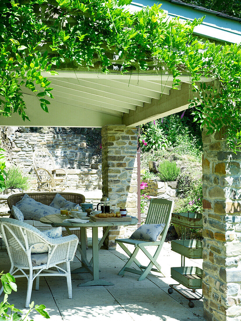 Frühstück auf dem Tisch einer schattigen Gartenterrasse