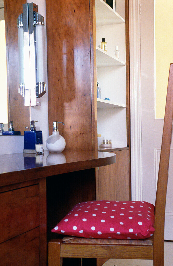 Red spotted cushion on chair a dressing table with pump action toiletries