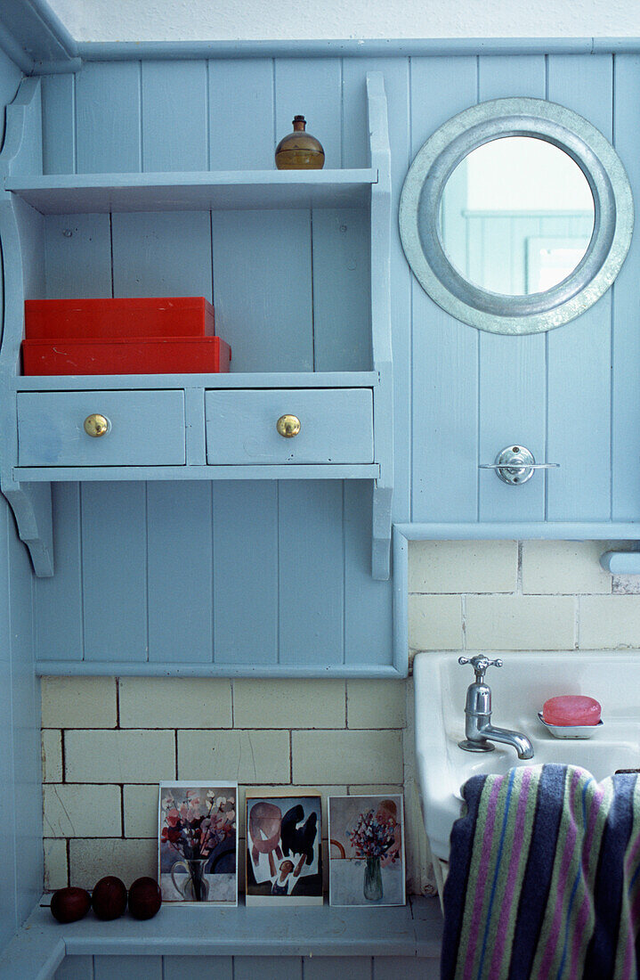 Wall mounted panelled bathroom cabinet and circular mirror