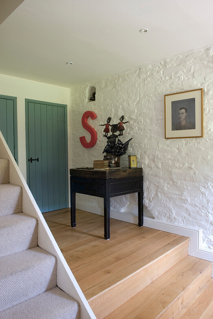 Antique side table on raised platform in whitewashed hallway