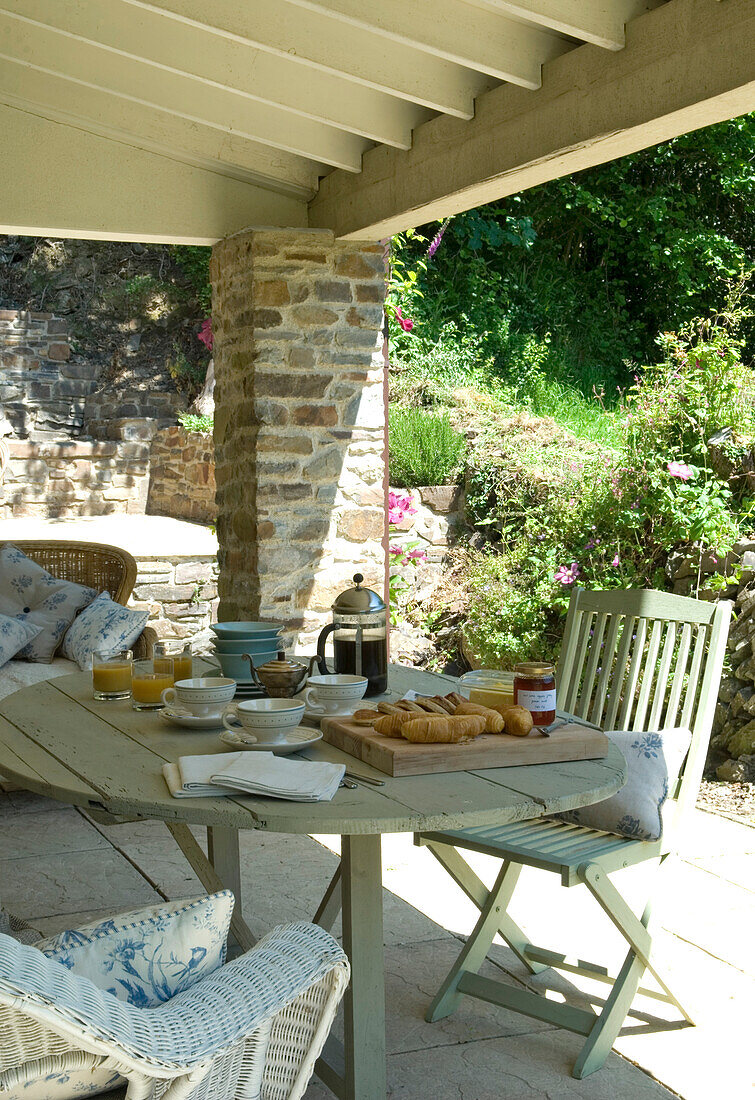 Cafetiere and croissants set on vendage table of porch extension