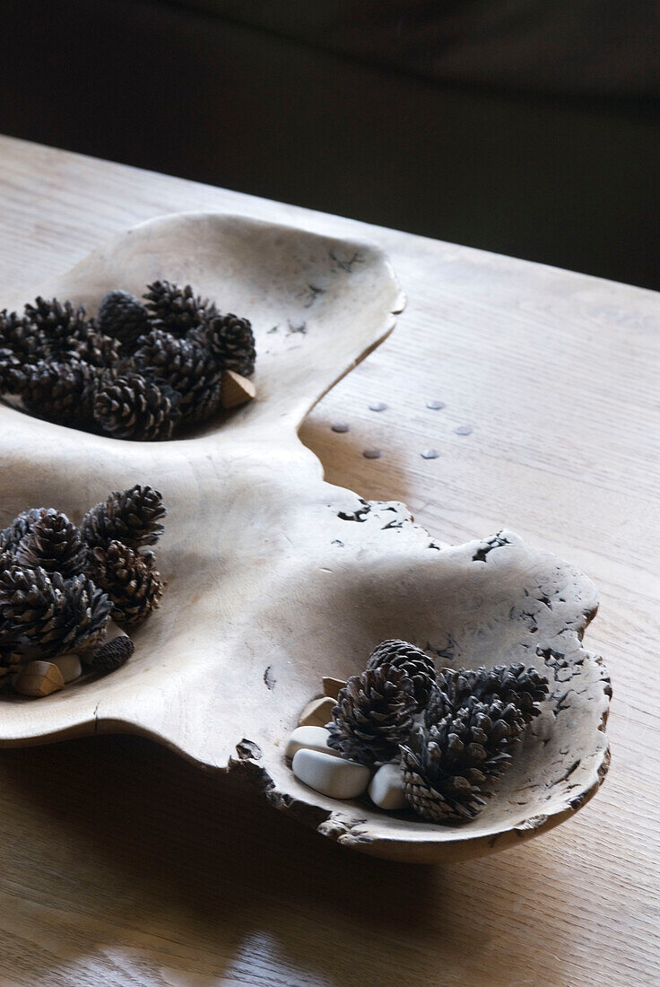 Detail of wooden dish on tabletop filled with pine cones