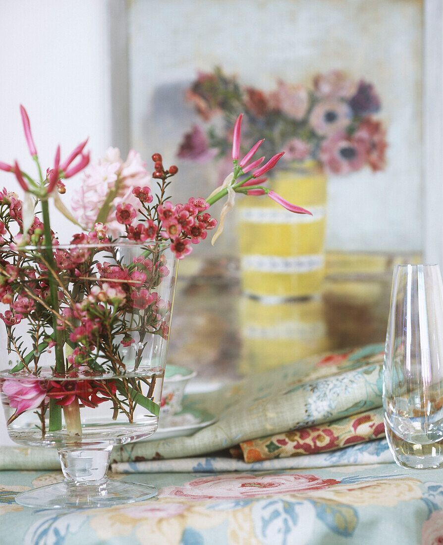 Vase mit Blumen auf geblümtem Stoff