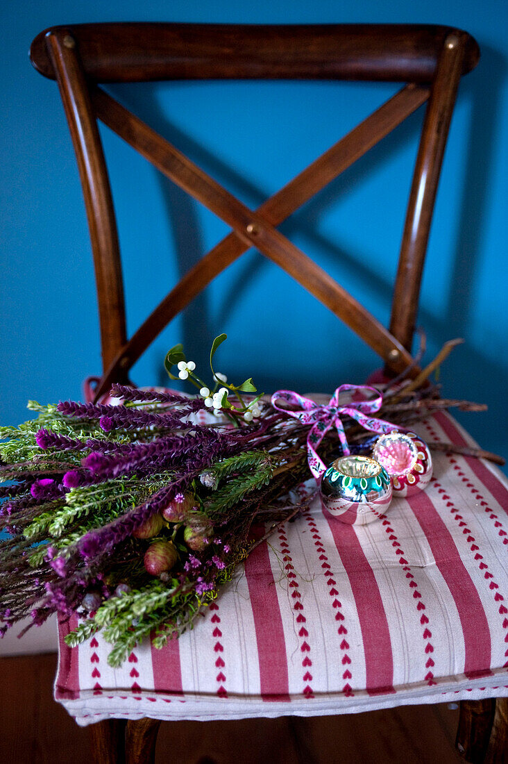 Blumensträußchen mit Weihnachtskugeln auf gemustertem Holzstuhl