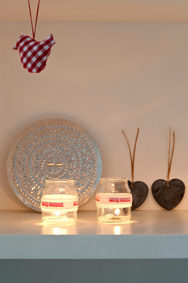 Christmas ornaments and lit candles on shelving 