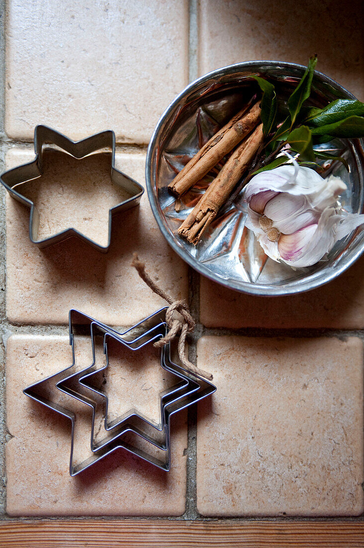 Star shaped biscuit cutters and cinnamon sticks in a metal tin