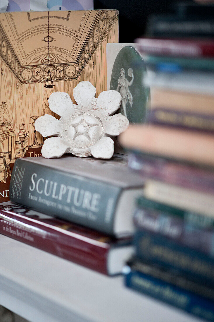 Flowerhead with reference books on mantlepiece in historic Yeovil home Somerset, England, UK