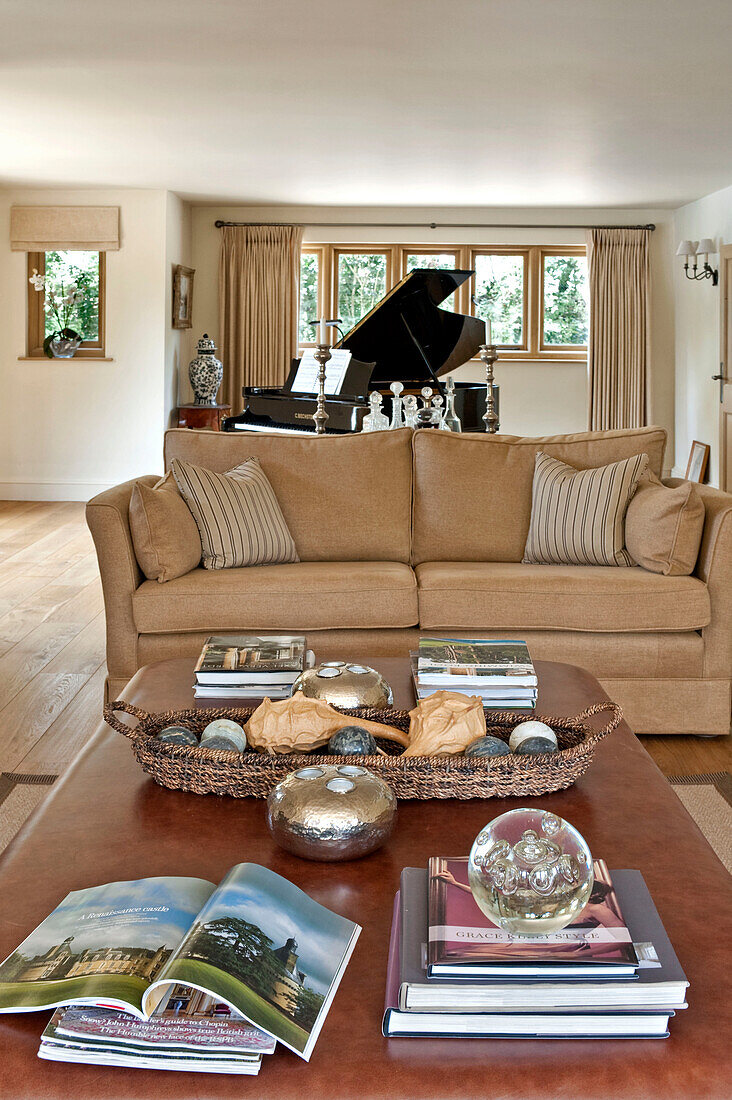 Grand piano and two seater sofa with coffee table and books in Canterbury home England UK